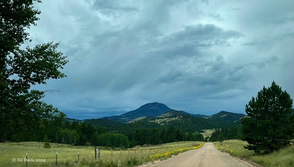 Photograph of a dirt road leading into green hills